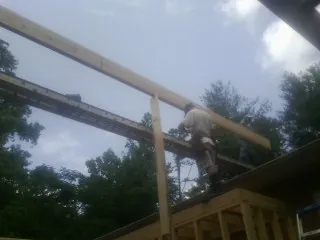 Carpenter setting a ridge beam over a new addition frame — Ice Dam Removal by Roofing Brothers in Clive