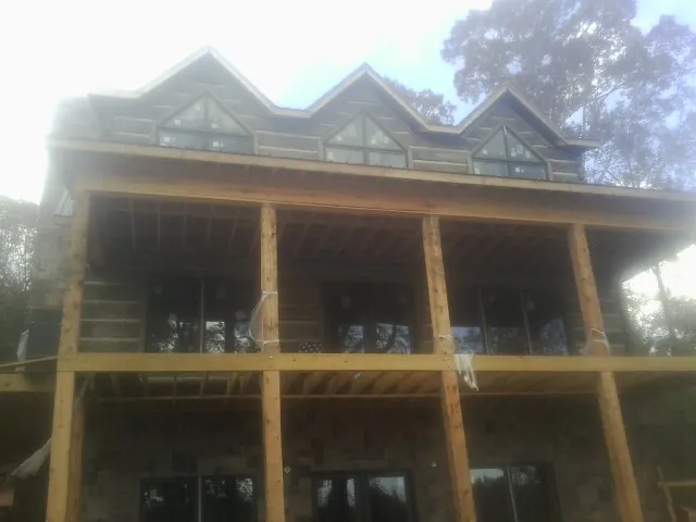 Dormers and porch framing on a large log home under construction — Roof Coating work by our crew in Clive