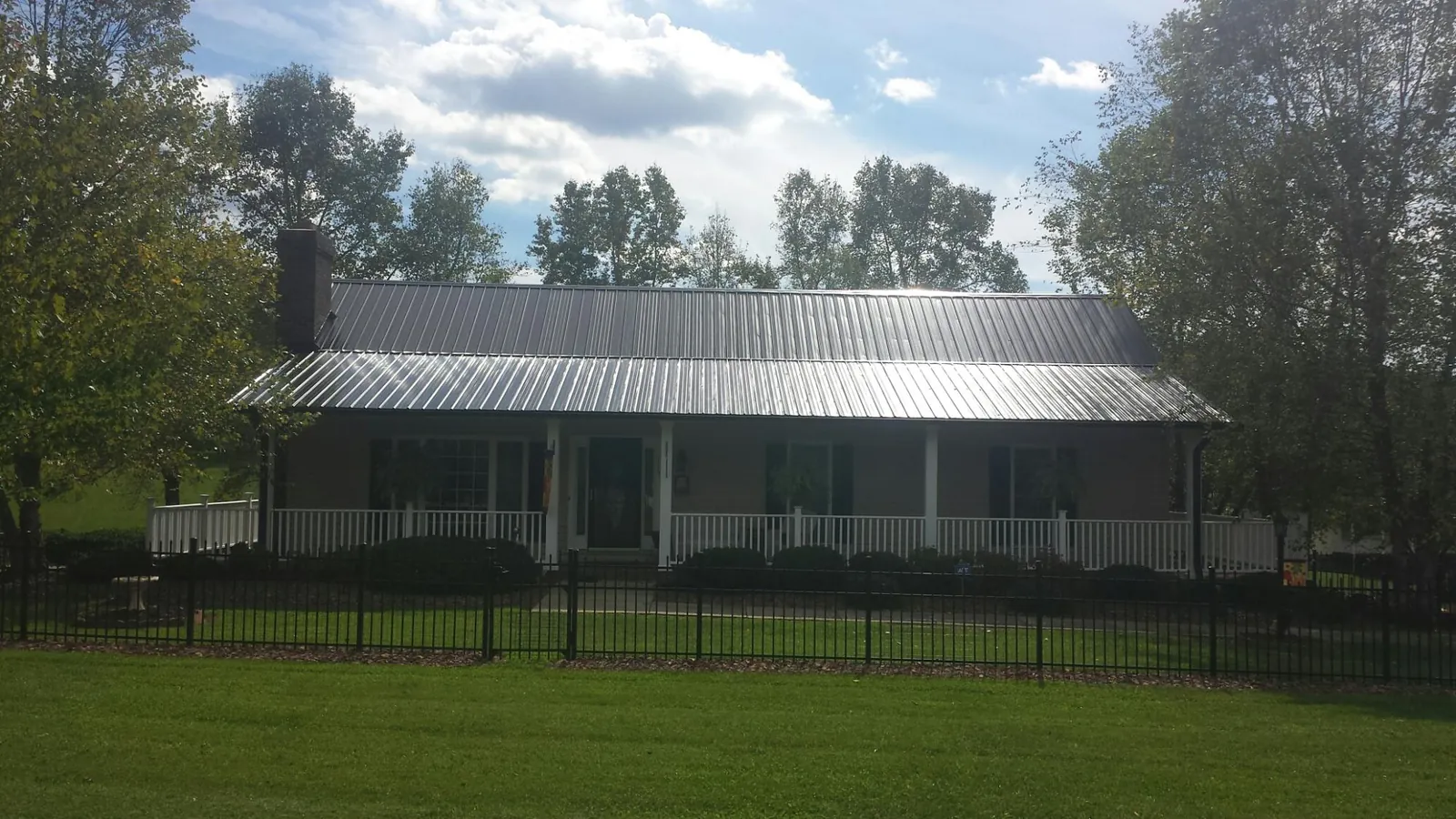 Gray metal roof on a brick ranch with a full width front porch — Gutter Guard Installation work by our crew in Clive