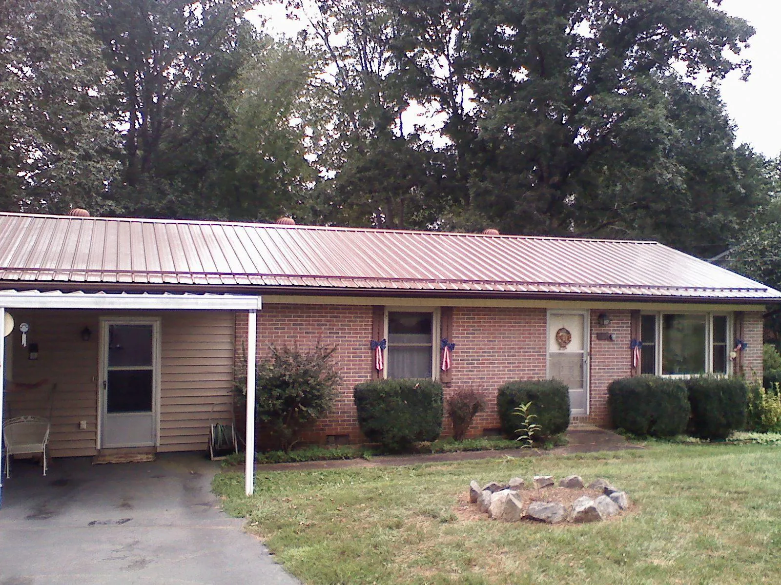 Bronze metal roof and carport on a brick ranch home — Roof Repair work by our crew in Clive