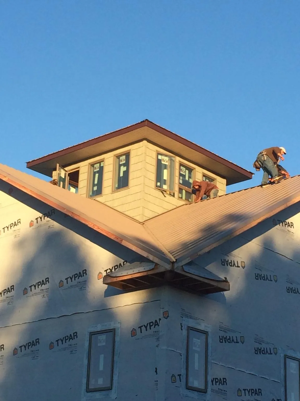 Roofers working around a rooftop cupola on a new metal roof at sunset — Roof Waterproofing in Clive by Roofing Brothers